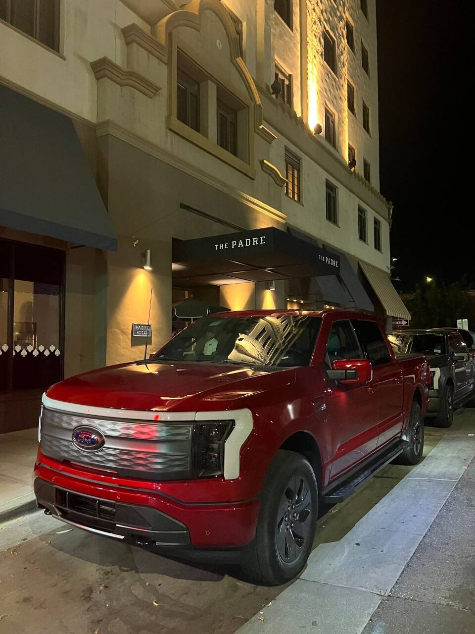A red Ford F-150 Lightning parked outside The Padre hotel.